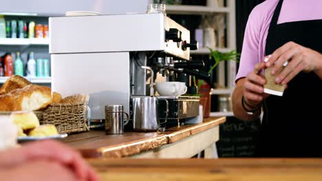 Waiter-serving-coffee-to-customer-at-counter