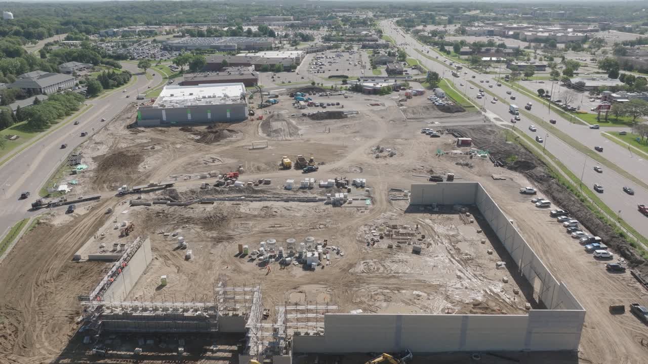 High angle aerial view of construction site during afternoon with a busy road beside it.