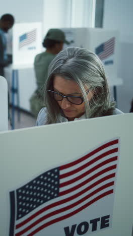 Elderly-woman-comes-to-vote-in-booth-in-polling-station-office.-National-Elections-Day-in-United-States.-Political-races-of-US-presidential-candidates.-Concept-of-civic-duty.-Slow-motion.-Dolly-shot.