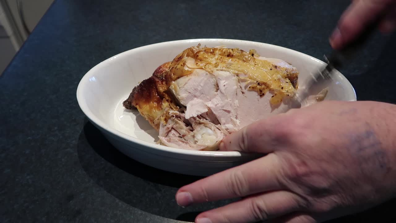 Man cutting or carving a hot roast chicken