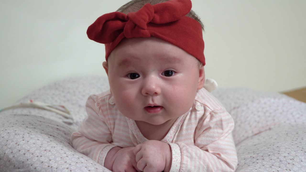 머리를 가까이 유지하려고 배에 누워 고군분투하는 유아 유아 작은 아이