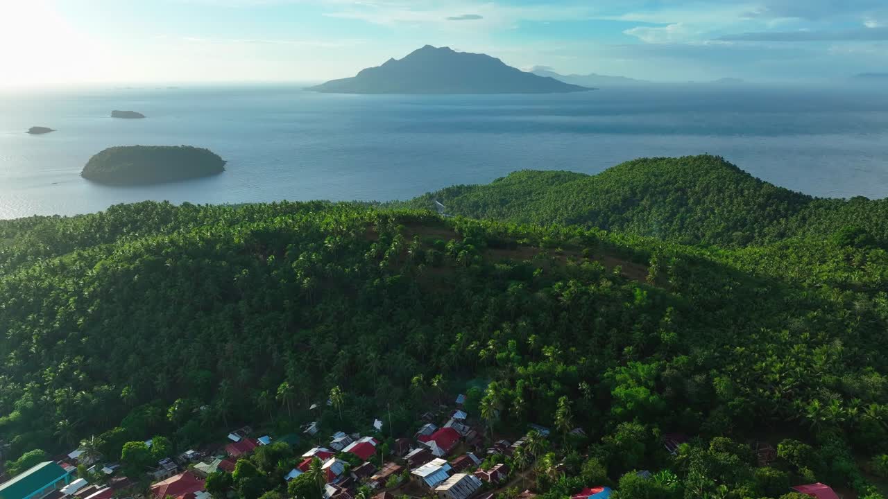 pequeño barrio asiático detrás de verdes montañas cubiertas y el mar durante el amanecer