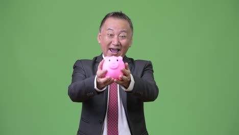 성숙 한 일본인 사업가 가 돼지 은행 을 들고
