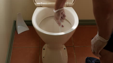 man cleaning household toilet bowl