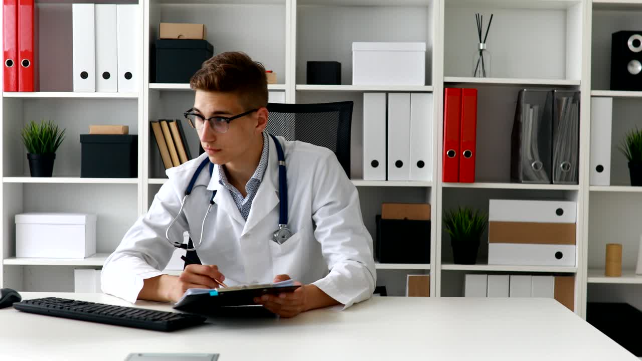 Jovem médico trabalhando com documentos no computador