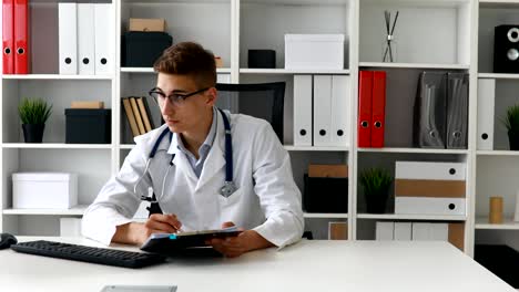joven médico trabajando con documentos en la computadora