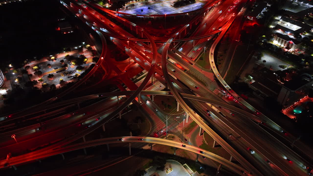 Flows of cars move to the different sides on the city. Busy interchange with red illumination at night from aerial view