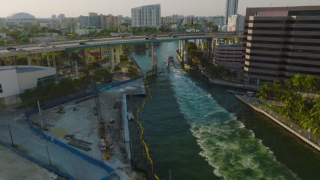 forwards tracking of ship passing under highway bridge in modern city. scene lit by late afternoon sun. miami, usa