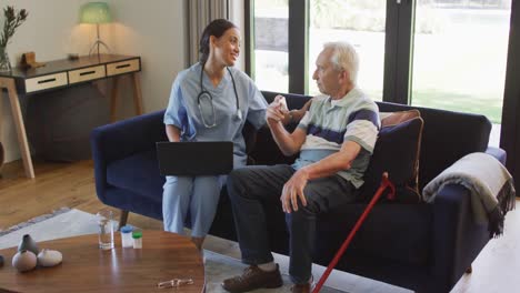 animación de un hombre mayor caucásico feliz hablando con una doctora biracial usando una computadora portátil
