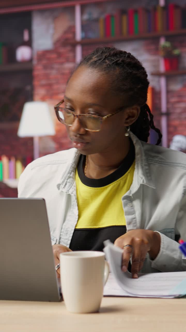 Vertical video Teleworker in apartment reading documents on notebook and taking notes