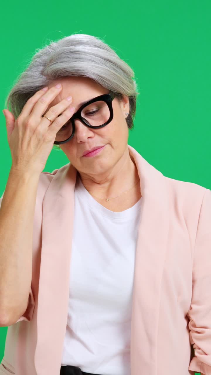 Donna matura con gli occhiali che mostra stress e stanchezza su schermo verde.
