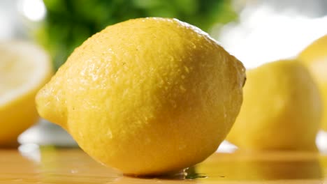 fresh lemon falling on wooden table, slow motion shot, blurred lemons in background