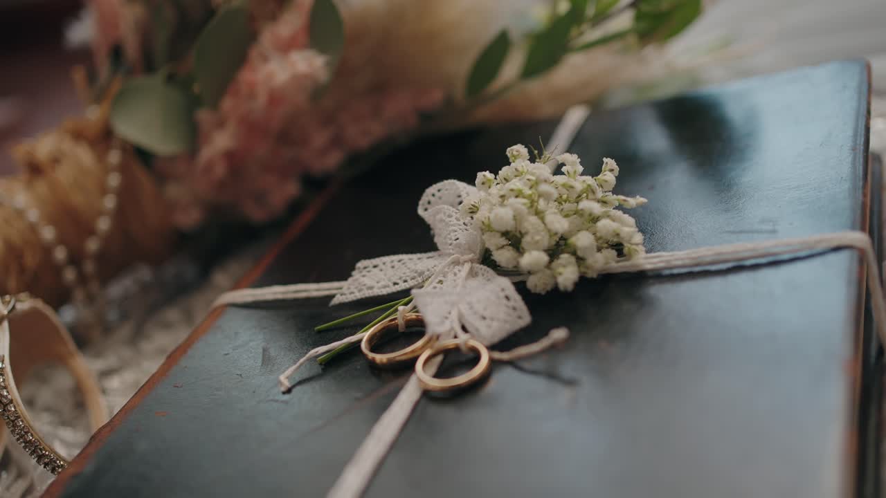Gold wedding rings on a Bible tied with lace and flowers, symbolizing faith and love