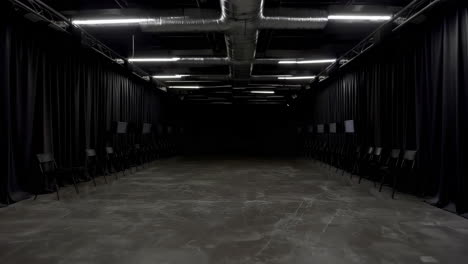 empty dark studio or performance hall with black curtains and rows of chairs