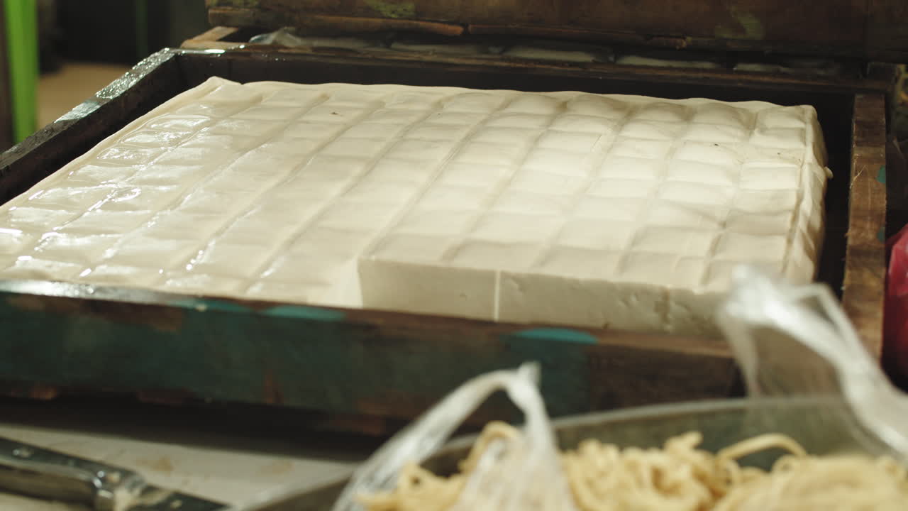 Hands picking raw fresh tofu from wooden container