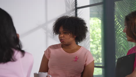 Group-Of-Women-Wearing-Pink-Breast-Cancer-Awareness-Ribbons-Meeting-And-Talking-At-Therapy-Support-Group-For-Cancer-Treatment-Patients-With-Counsellor-2