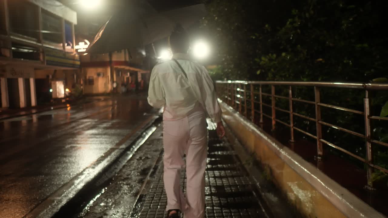 A woman walks in the rain at night