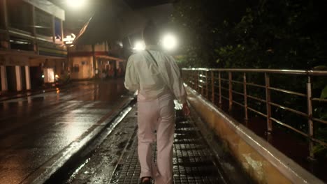 a woman walks in the rain at night