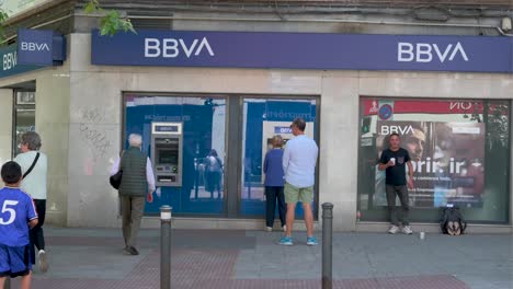 people using an atm at a bbva bank in spain