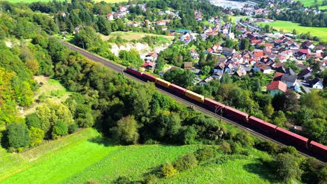 Luftdrohne-über-Einem-Güterzug,-Der-An-Einem-Ländlichen-Dorf-Vorbeifährt-4k