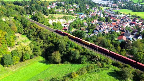 dron aéreo sobre un tren de mercancías que pasa por una aldea rural 4k