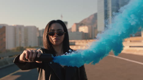 girl playing with blue smoke bomb in city street slow motion