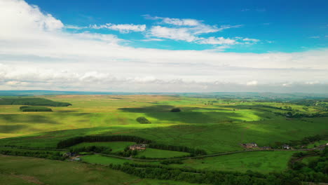 aerial landscape shot showing lush green farmland, on a bright blue sky day