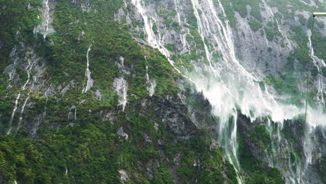 temporary waterfalls forming in milford sound after heavy rainfall