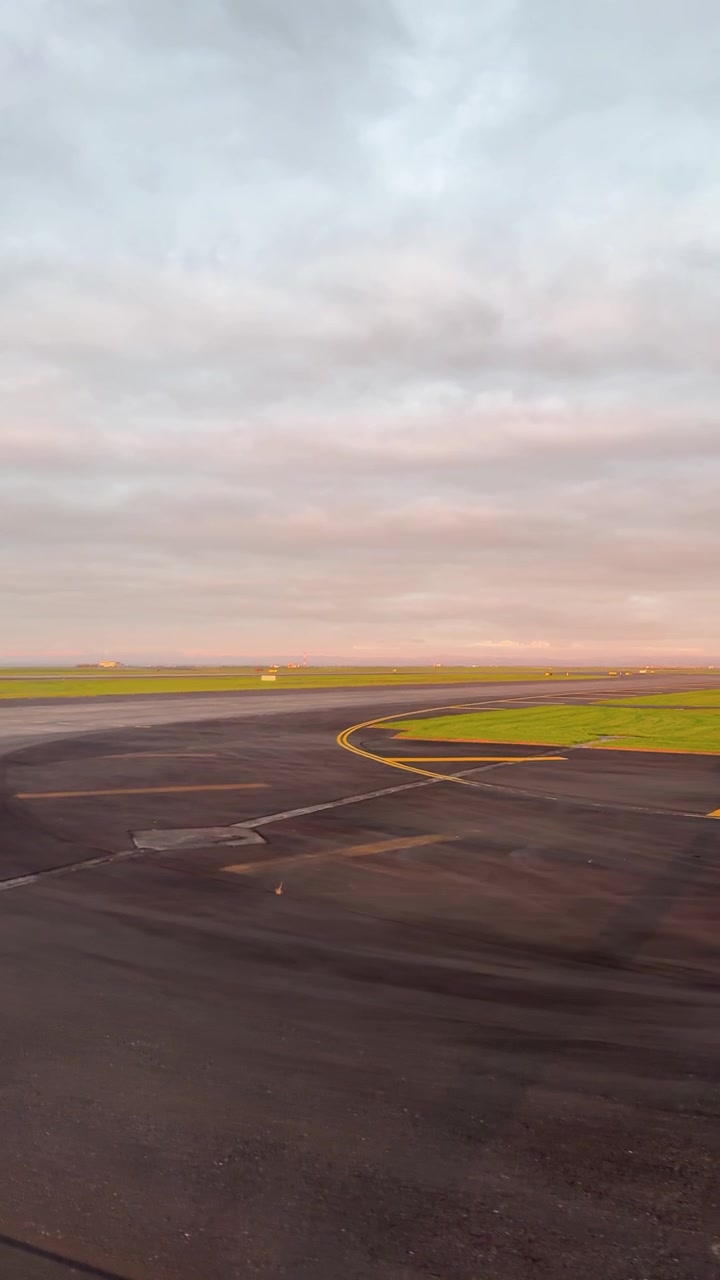 Pesawat melaju di landasan pacu Auckland saat matahari terbit, menangkap langit yang tenang dan cakrawala yang cerah. Gerakan kamera yang mulus meningkatkan suasana yang tenang