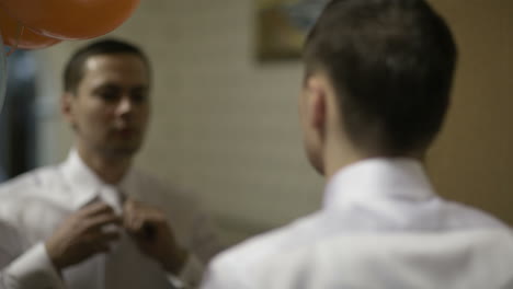 el novio arreglando su corbata.