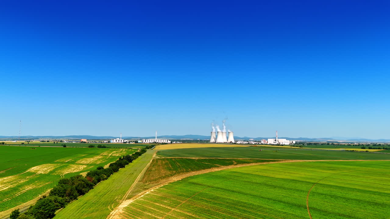 Power plant in the vast green plantations. Industrial factory located away from the city in the countryside.