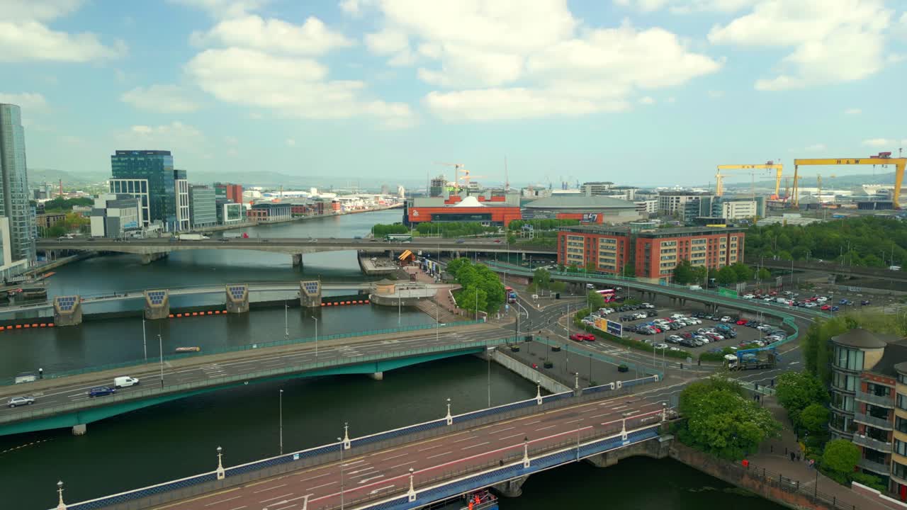 Reversing aerial video of Belfast City Centre in Northern Ireland, UK on a bright sunny day. Cars travel along the roads over the River Lagan. Filmed in 4K, 60FPS and in Rec709 Color.