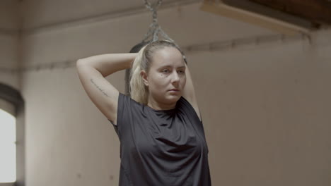 Medium-shot-of-tired-woman-stretching-arms-after-boxing-workout