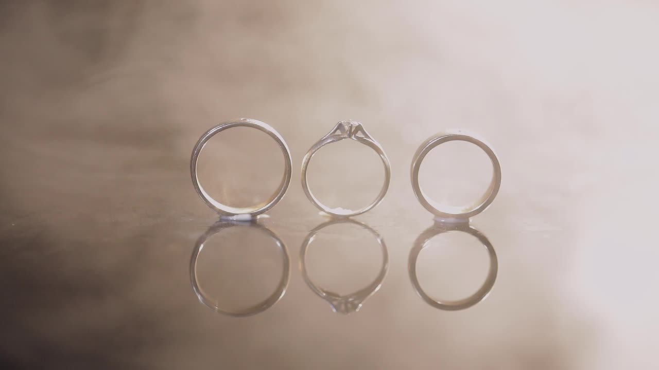 Wedding and engagement rings lying on dark water surface shining with light