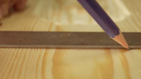 a macro shot of carpenter using a pencil and hardwood square on a peice of timber