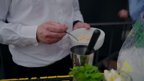 Bartender-adding-golden-sugar-to-a-cocktail-shaker-with-fresh-mint-and-lemon-garnish