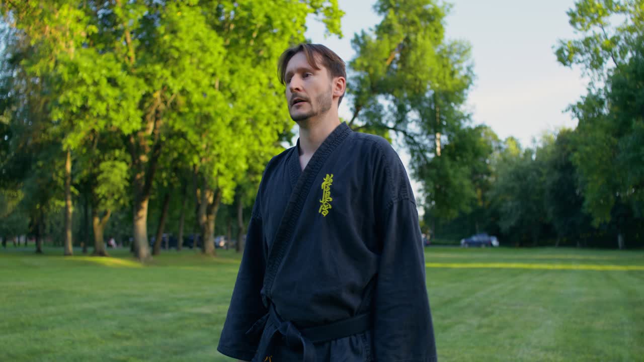 Uomo in uniforme da karate che pratica arti marziali all'aperto