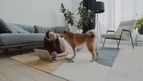 Niña-Juega-Con-Su-Perro-Mientras-Trabaja-En-Su-Computadora-Portátil-En-Casa