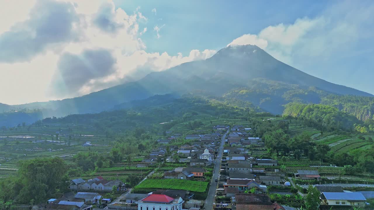 Vista aerea del sole che illumina una splendida campagna tropicale con sfondo montuoso. Villaggio di Stabelan, Vulcano Merapi. Campagna indonesiana