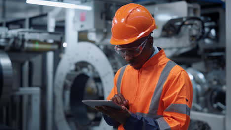 Profesional-Afroamericano-Analizando-El-Trabajo-Logístico-En-Una-Enorme-Fábrica-Moderna.