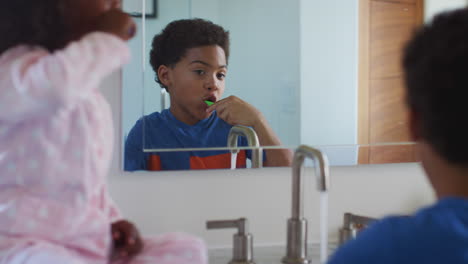 Brother-And-Sister-Brushing-Teeth-Reflected-In-Bathroom-Mirror-At-Home