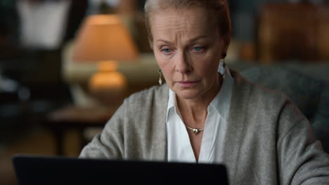 Portrait-focused-old-woman-working-laptop-computer-in-vintage-living-room.