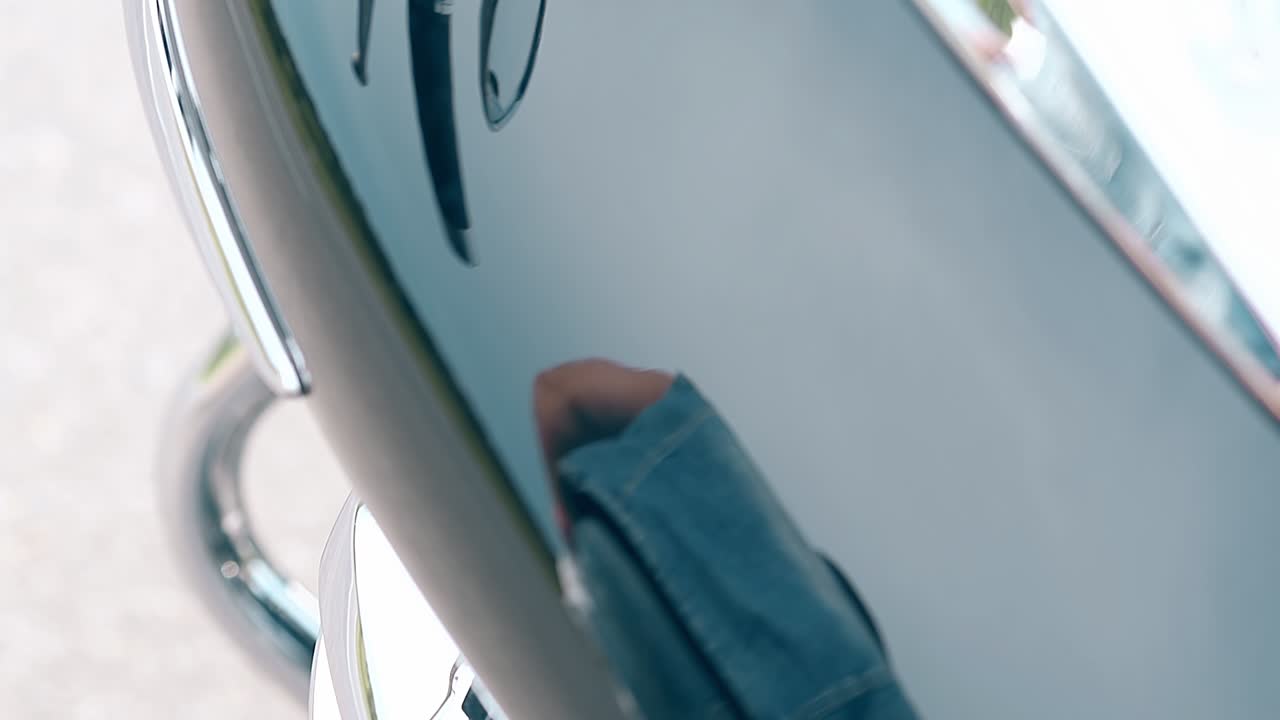 el tanque de gas de la motocicleta negra de primer plano refleja a un hombre caminando