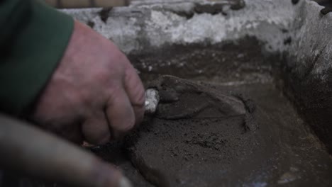 Close-up-of-a-person's-hands-spreading-wet-concrete-with-a-trowel-in-construction-work