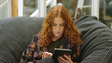 Businesswoman-sitting-on-the-armchair-and-using-digital-tablet-4k