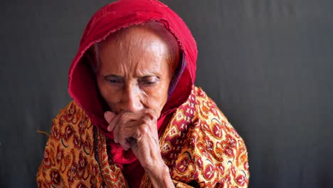 portrait of a sad elderly woman in a red headscarf