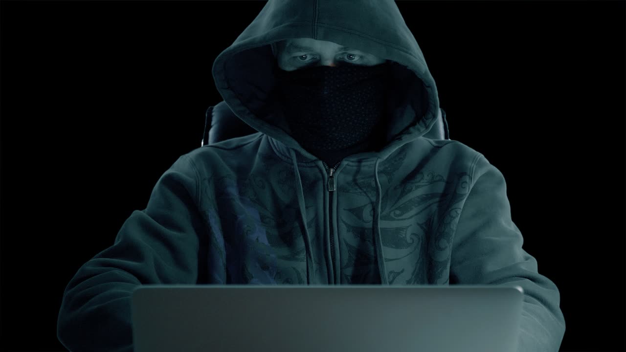 un hombre con capucha sentado en la mesa y codificando en la computadora portátil. noche oscura. vista delantera de cerca. hacker con máscara de balaclava trabajando en la ordenador. canal alfa clave de croma fondo transparente.