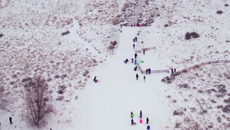 一座雪地覆蓋的山丘的空中圖片,有幾<unk>孩子在新鮮粉末中玩