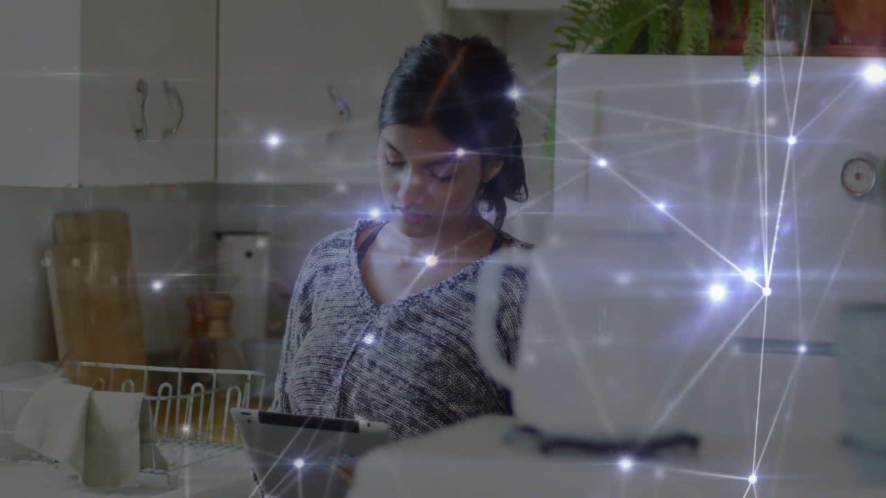 adult woman tapping tablet inside kitchen, using smart home technology with glowing network overlay