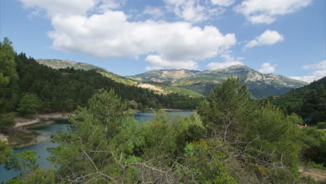 Time-lapse:-white-stratus-and-cumulus-clouds-wisps-and-patches-above-Tsivlou-lake,-Greece,-wide-view